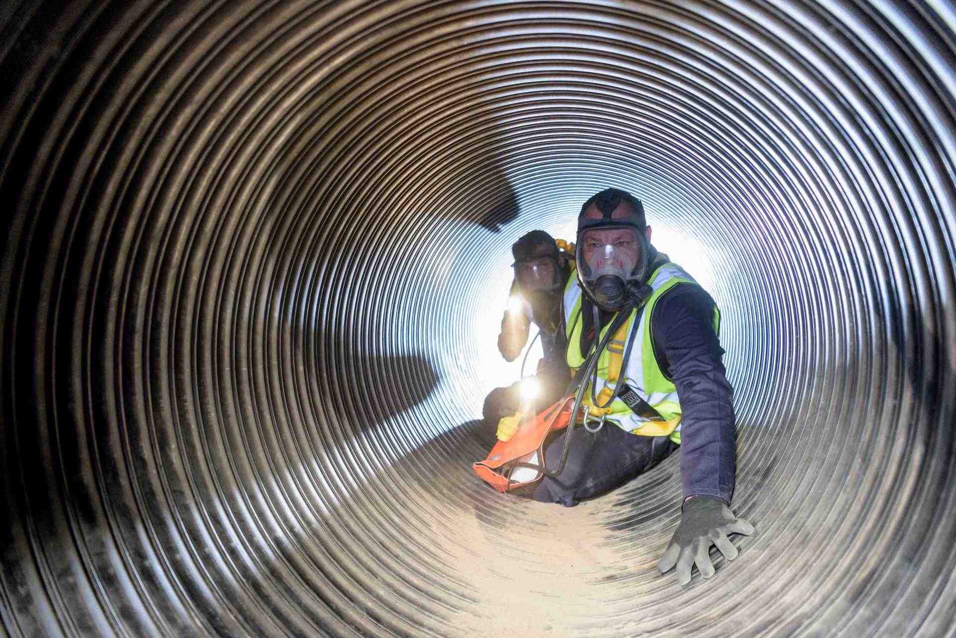 2 Employees wearing safety protection equipments going through a confined space training